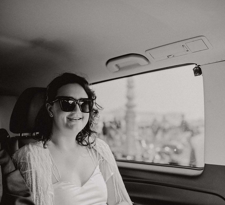 Bride wears sunglasses on her wedding day whilst sat in car 