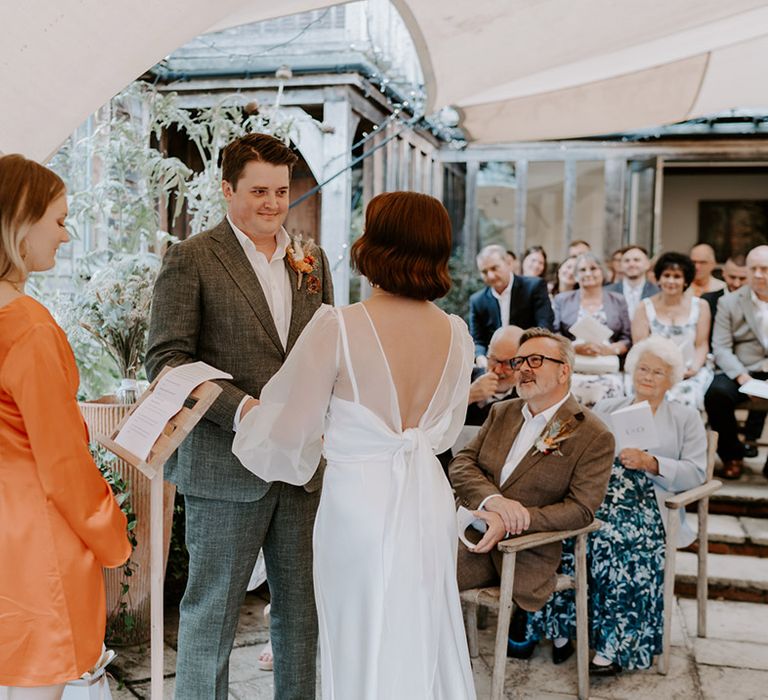 Bespoke wedding ceremony at The Copse County House with bridesmaid in orange satin dress conducting the ceremony 