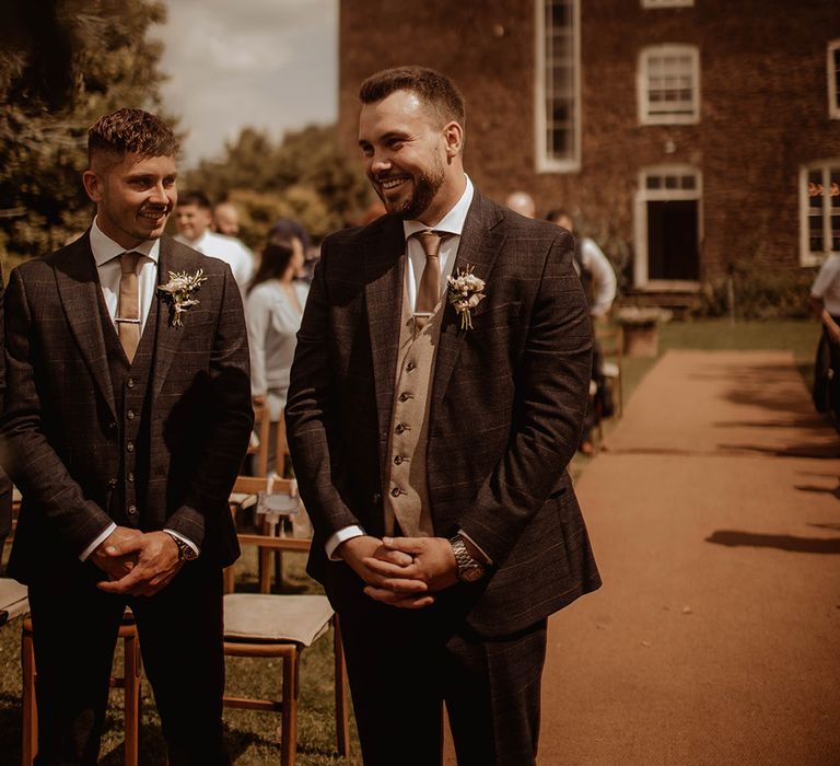 groom and best man in check suits at the altar of an outdoor wedding at Dewsall Court