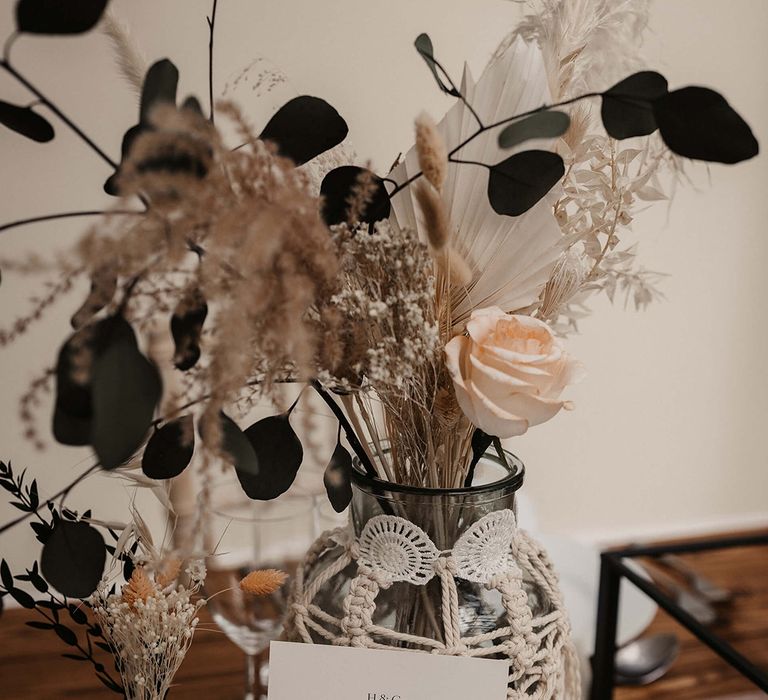 Wedding stationery in front of vase covered in macrame 