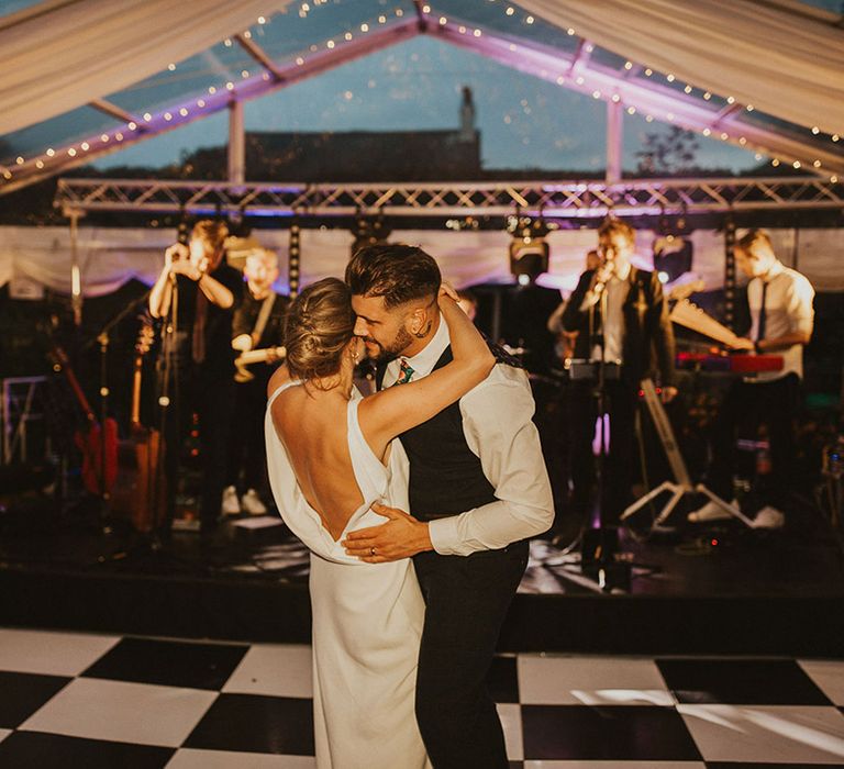 Bride and groom first dance in a clear marquee with bride in a low back Charlie Brear wedding dress