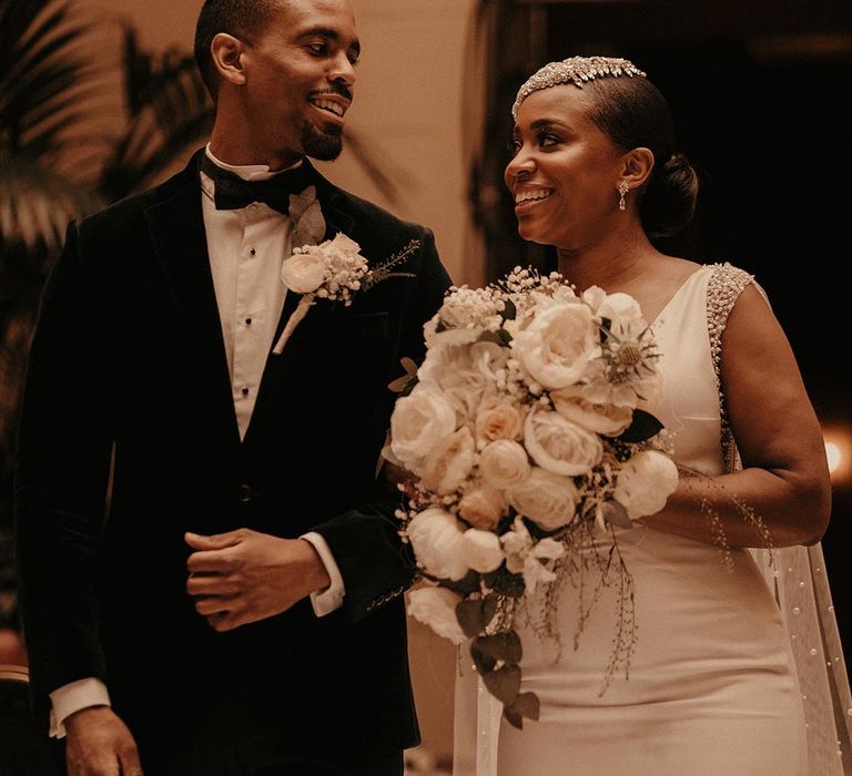 Black tie wedding with Black bride in a fitted wedding dress holding an all white wedding bouquet 