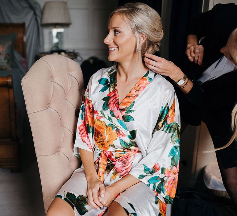 Bride in silk floral dressing gown gets her hair done on wedding morning