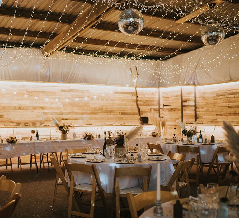 Rustic wedding venue with pampas grass, disco balls, fairy lights with a white, neutral theme