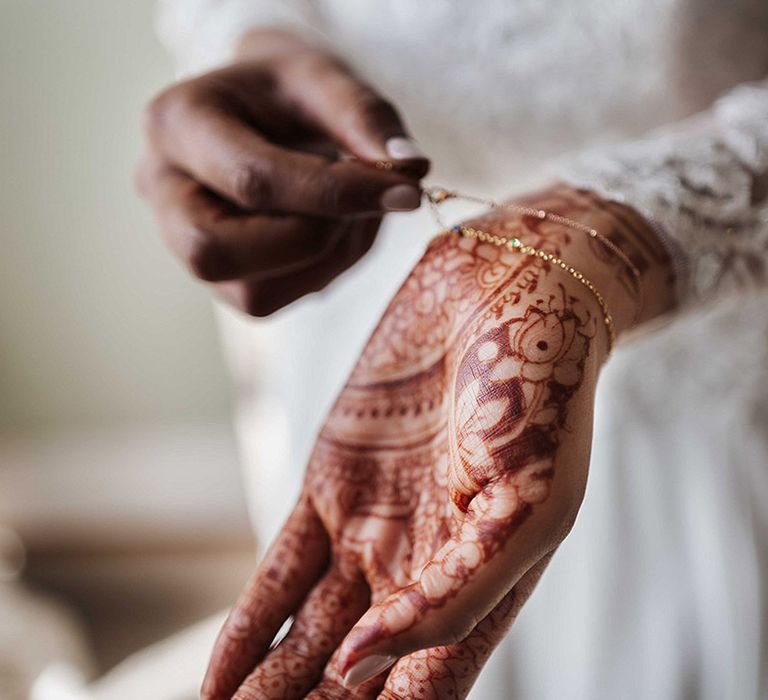 Bride wearing dainty gold bracelets and traditional henna for wedding