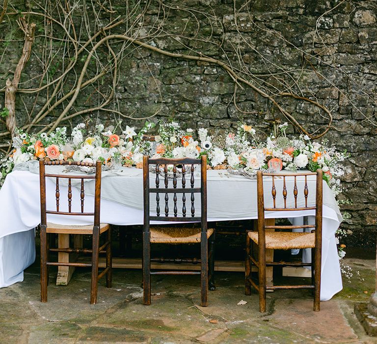 outdoor wedding reception table in the gardens at Holesfoot Cumbria with cascading flower table runner 