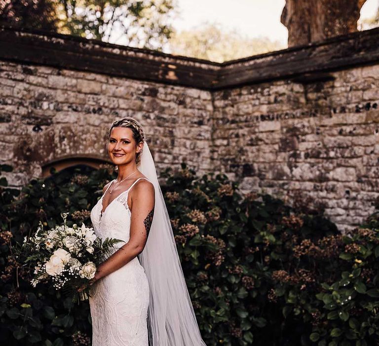 Bride in lace wedding dress with train and veil for outdoor wedding at Athelhampton House