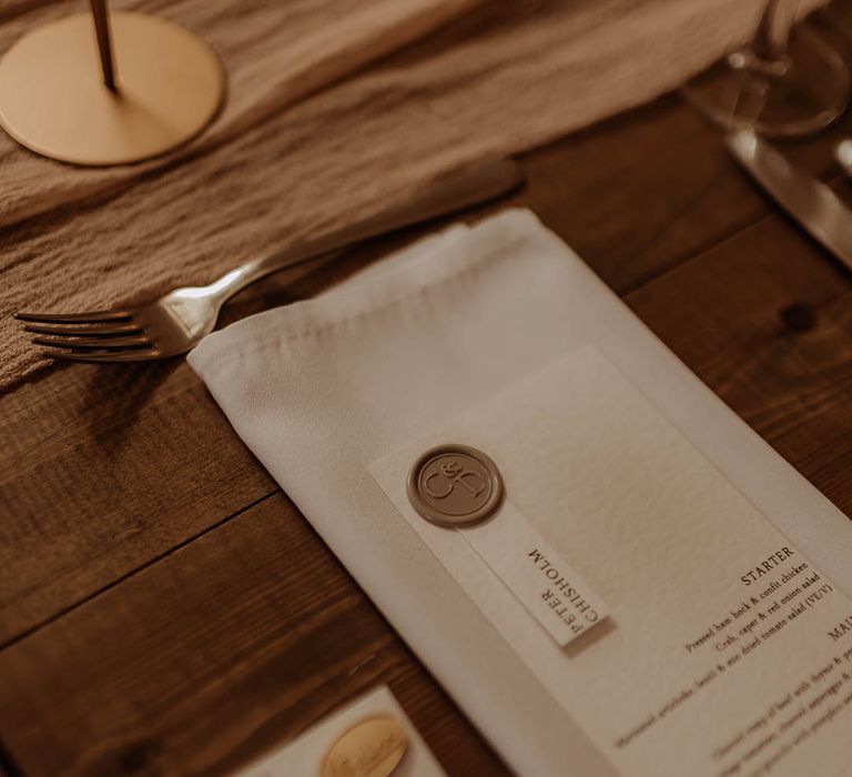 White napkin with white wedding menu with gold wax seal decoration for boho luxe wedding 