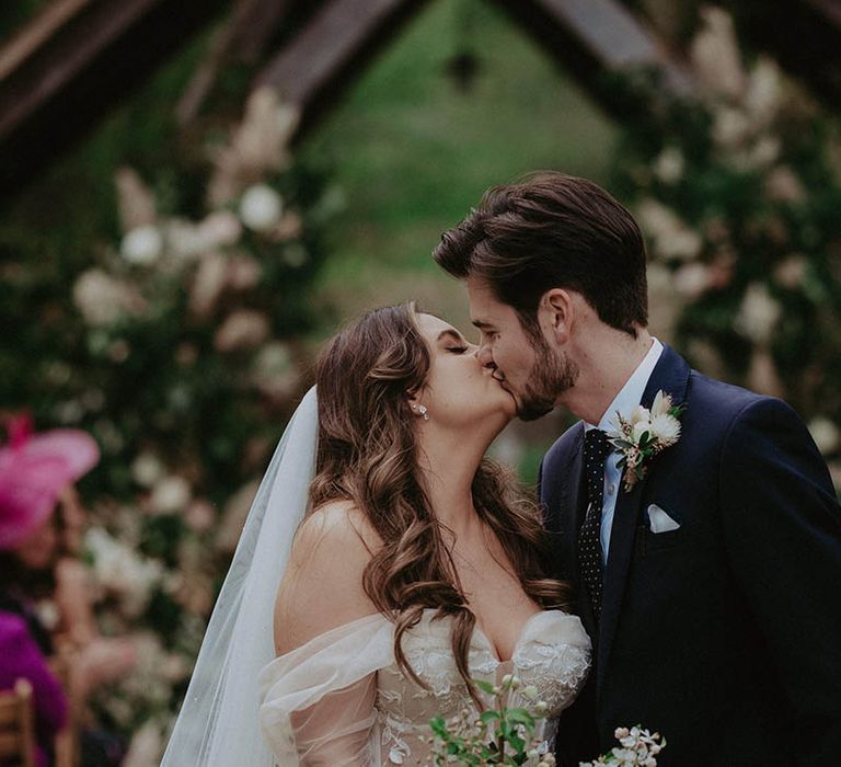 Bride and groom share a kiss for their outdoor wedding at Millbridge Court