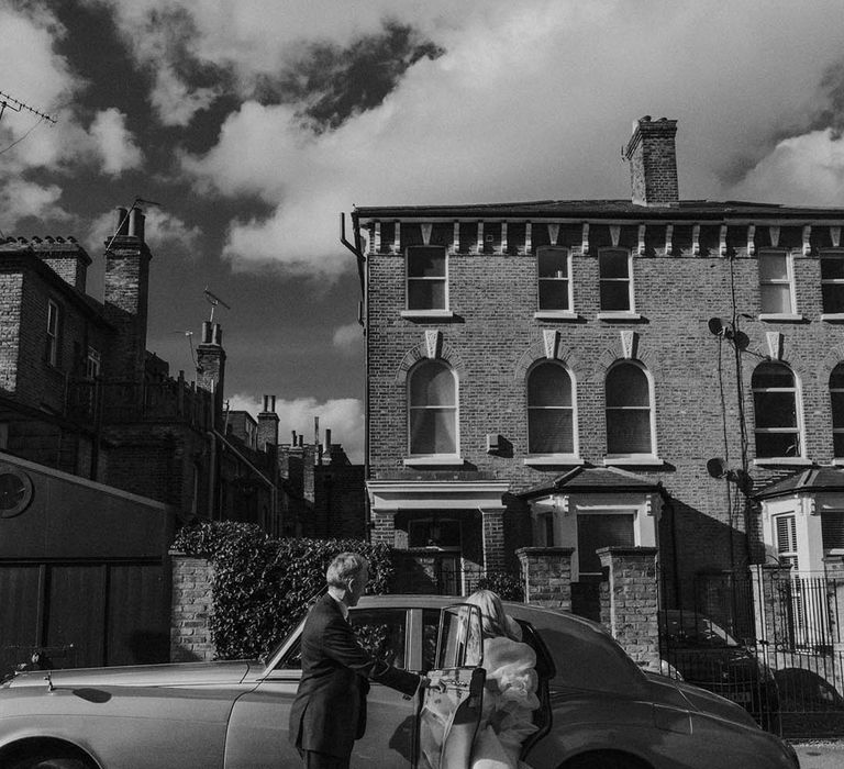 Bride getting into a vintage wedding car at modern stylish London wedding 