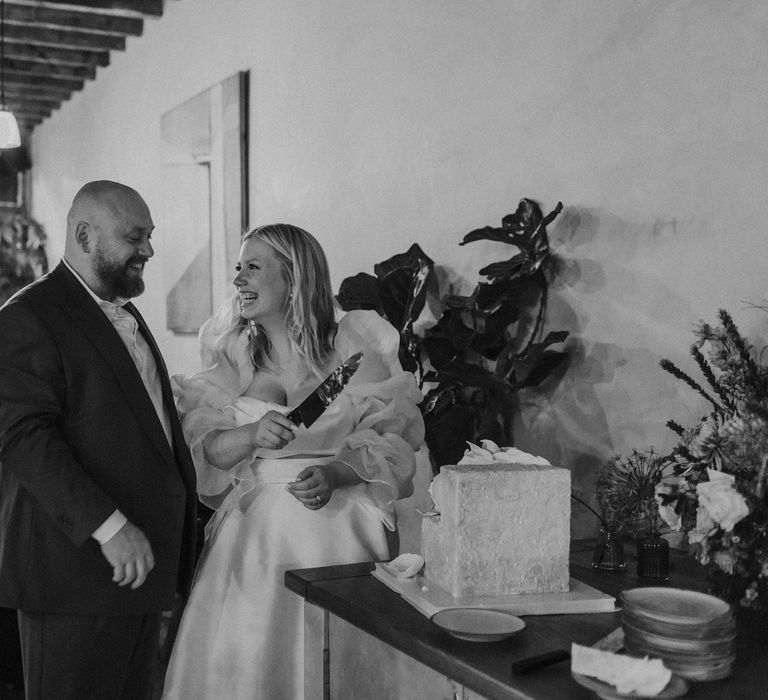 Bride and groom cutting their square wedding cake at evening reception 