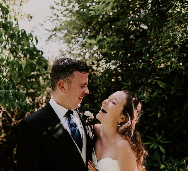 Bride wearing Suzanne Neville princess wedding dress looks lovingly at her groom outdoors on their wedding day