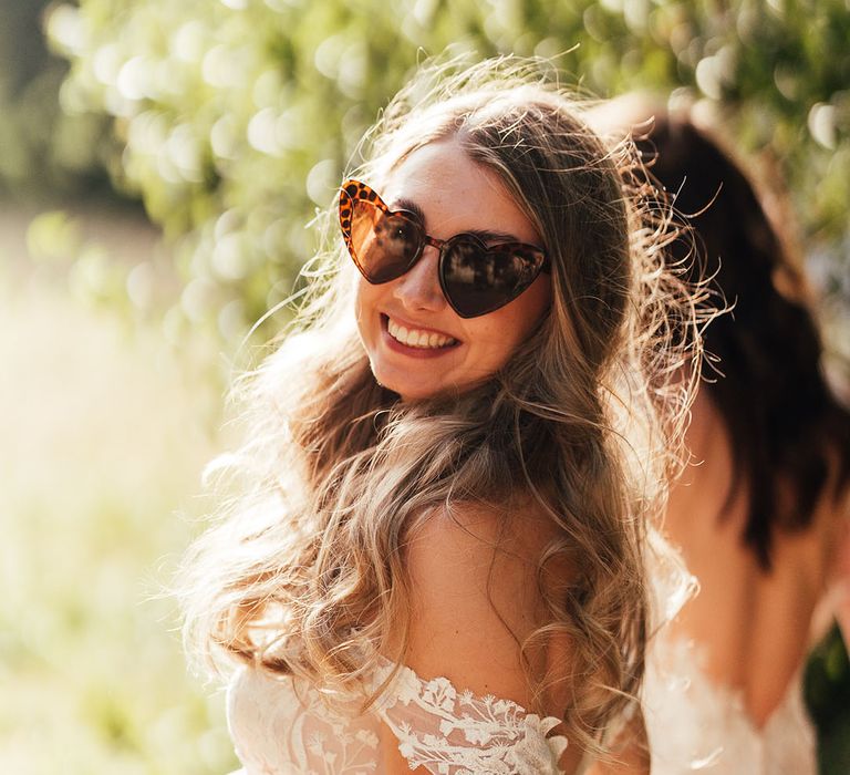 Bride in retro heart shaped sunglasses on her wedding day 