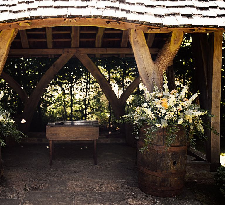 Cripps Barn outdoor wedding ceremony area with barrels full of wedding flowers 