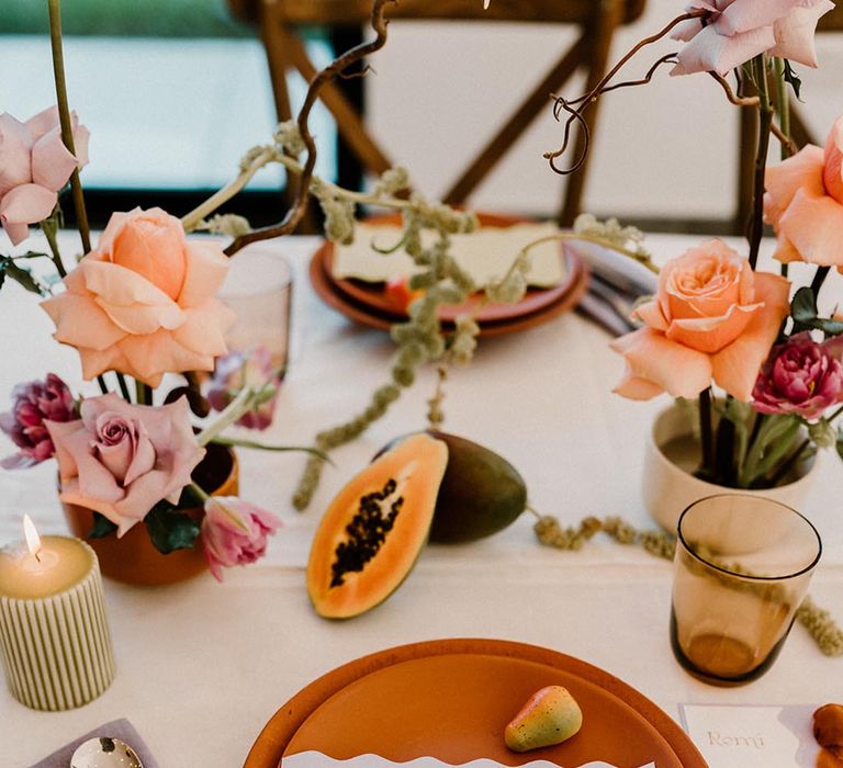 Colourful wedding tablescape with terracotta plates, lavender napkins, fru8it decor and pops of colour with the flowers and candles 