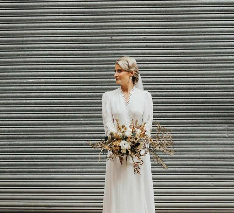 Bride wears her blonde hair tied into low up-do with Reformation wedding dress with scalloped lace edging 