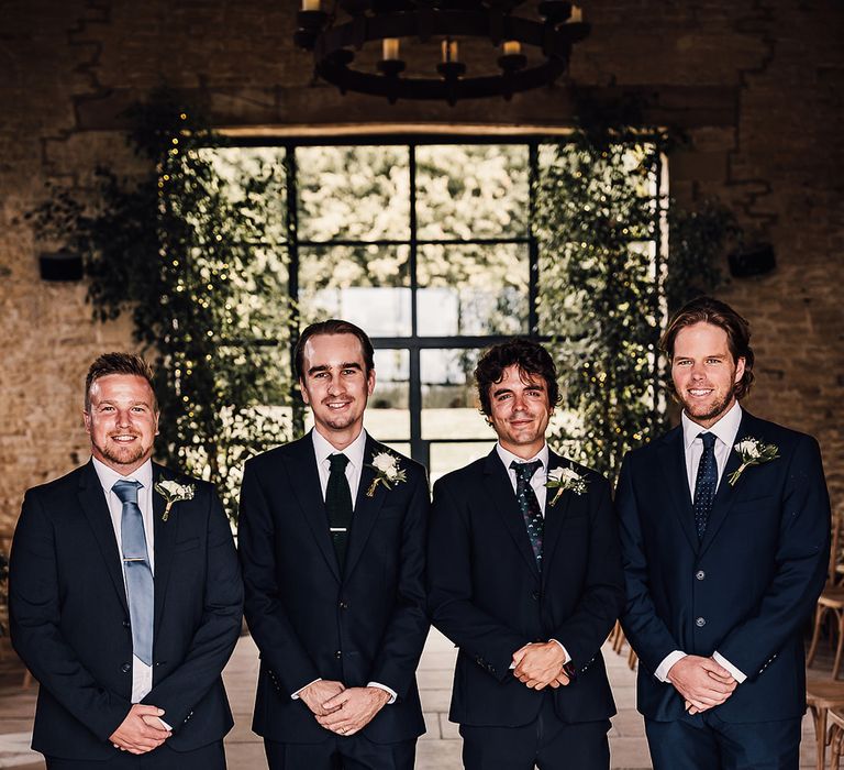 Groom with the groomsmen in navy blue suits and different colour and style ties 