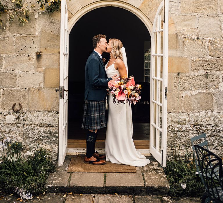 Bride & groom kiss in doorway after wedding ceremony at Shortflatt Tower