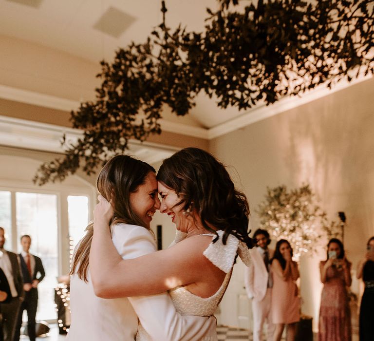 Bride in a halter neck white sparkly dress sharing the first dance with the bride in a white suit 