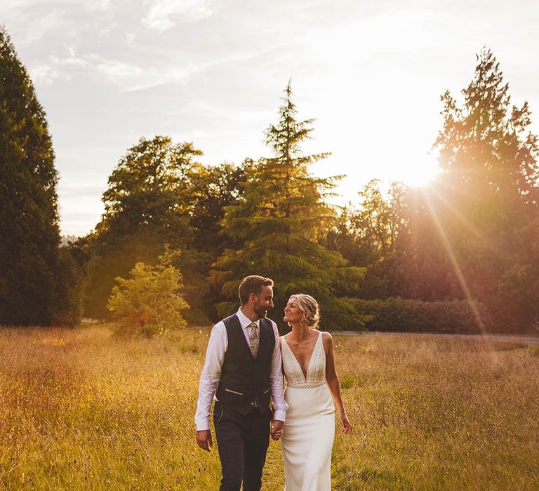 Win wedding photography from We Are // The Clarkes. This wedding photo shows golden hour featuring Bride and Groom walking through field