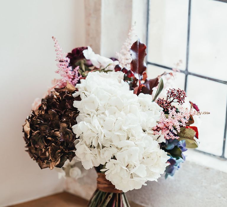 White, brown, and blue hydrangea bridal bouquet for winter Christmas wedding at Notley Abbey 