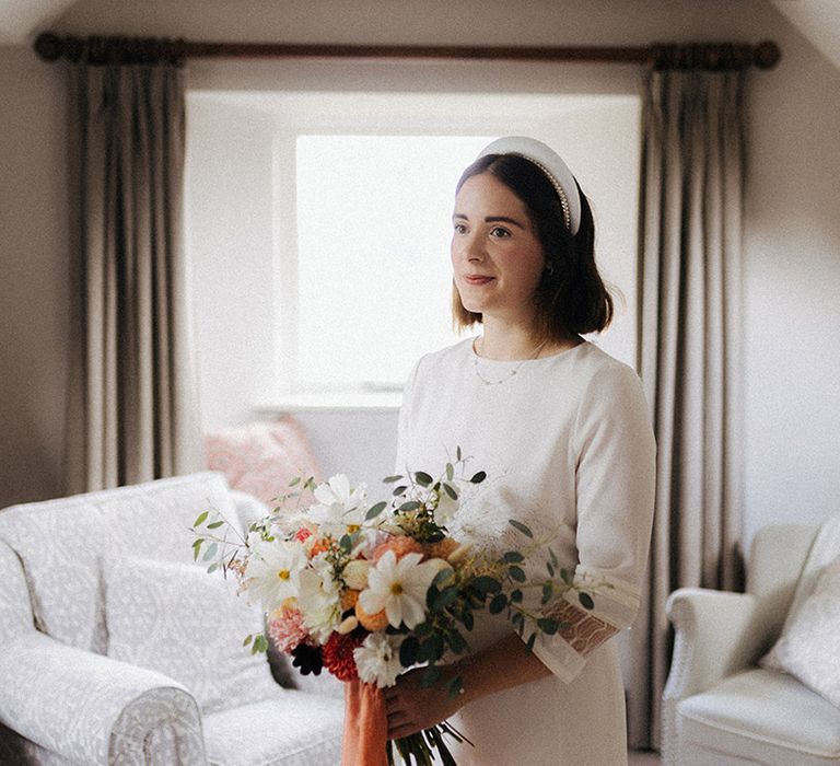 Bride in high neck with three quarter length sleeves with a chunky wedding headband with a handgrown wedding bouquet with white cosmos and dahlias 