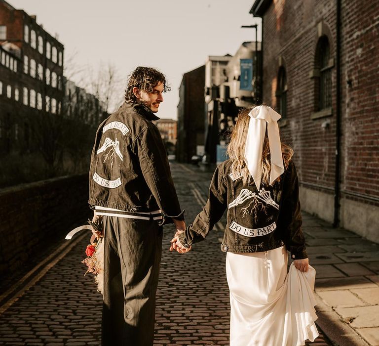 Bride and groom wearing matching personalised black denim jackets with white embroidery 