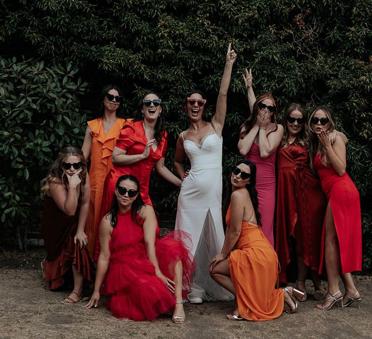 Fun bridal party portrait with bride in a Stephanie Allin bridal gown and bridesmaids in mismatched pink, red, orange & rust bridesmaid dresses