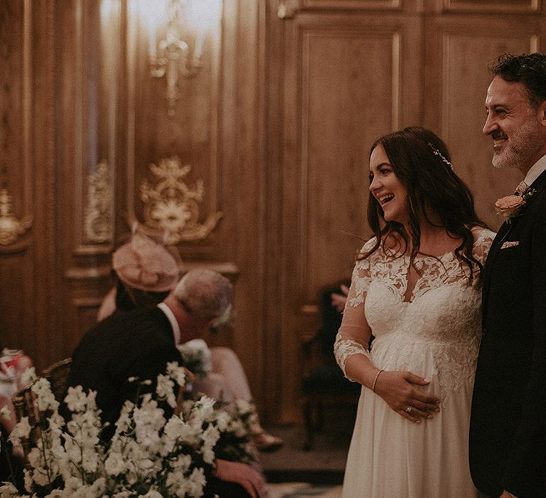 Mature groom in dark suit stands at the altar smiling at their guests after being married at their Claridge's wedding 