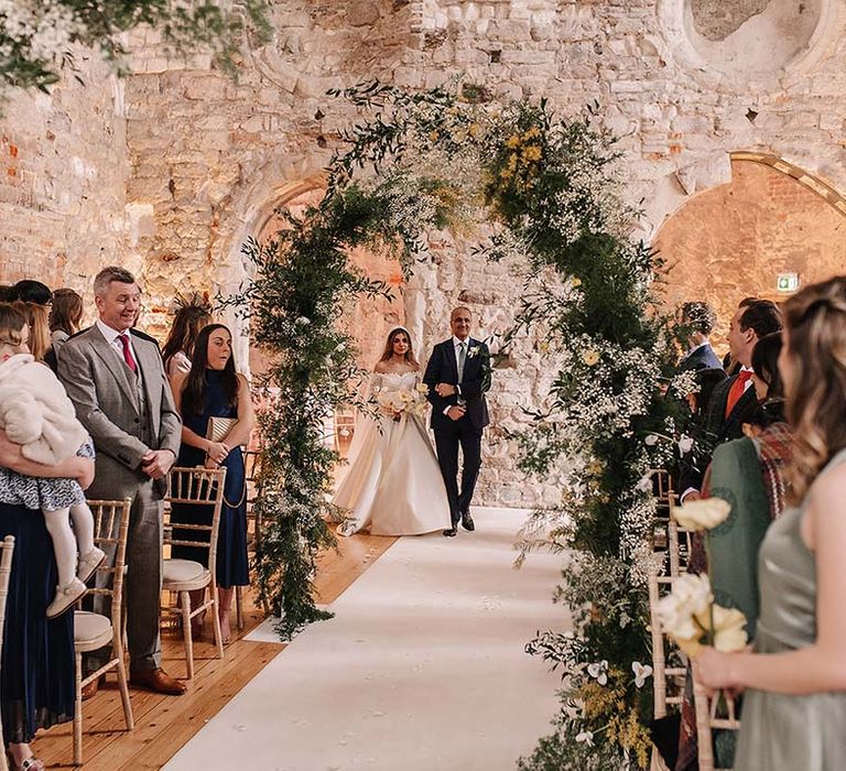 Deconstructed floral arch column arrangements decorating the aisle with the bride being walked down the aisle by her father 