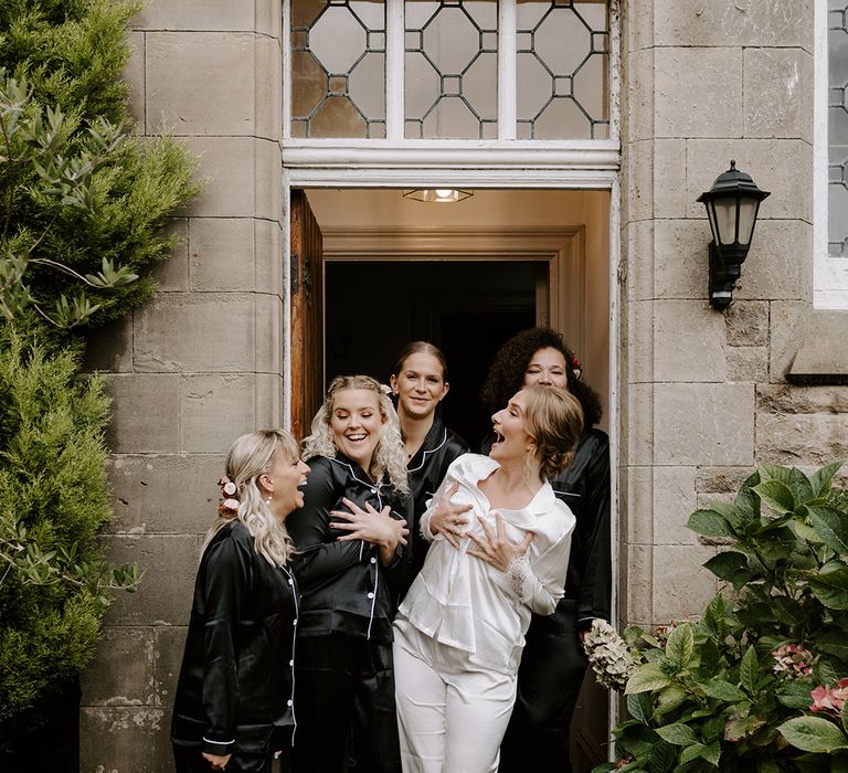 Bridesmaids in black satin pyjamas with the bride in white satin pyjamas for the wedding 