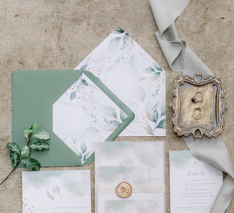 flat lay of green and white wedding stationery suite with invitation, envelope, details and RSVP card