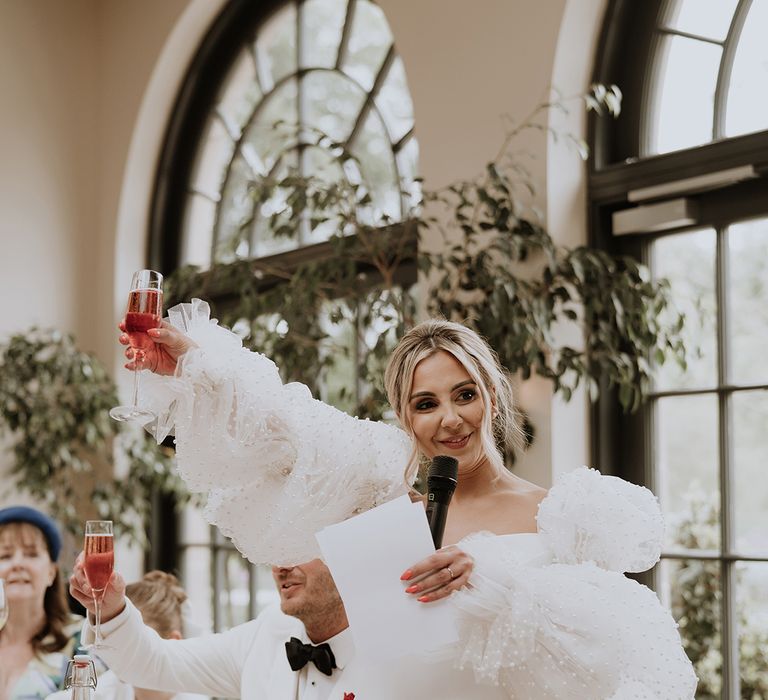 Bride stands with microphone to read out her wedding speech making a toast 