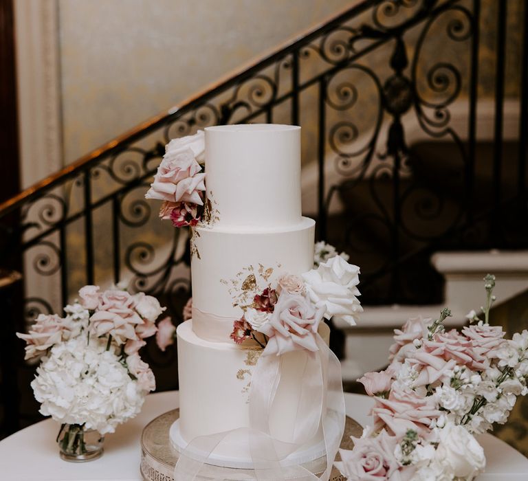 Three tier white iced wedding cake with pink ribbon 