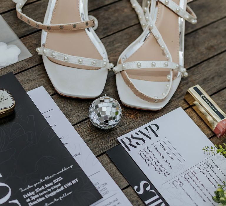 Monochrome wending stationery flat lay with the bride's pearl wedding shoes and jewellery 