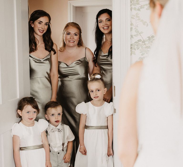 Bridal party wearing green satin bridesmaid dresses with flower girls and page boys in green outfits 