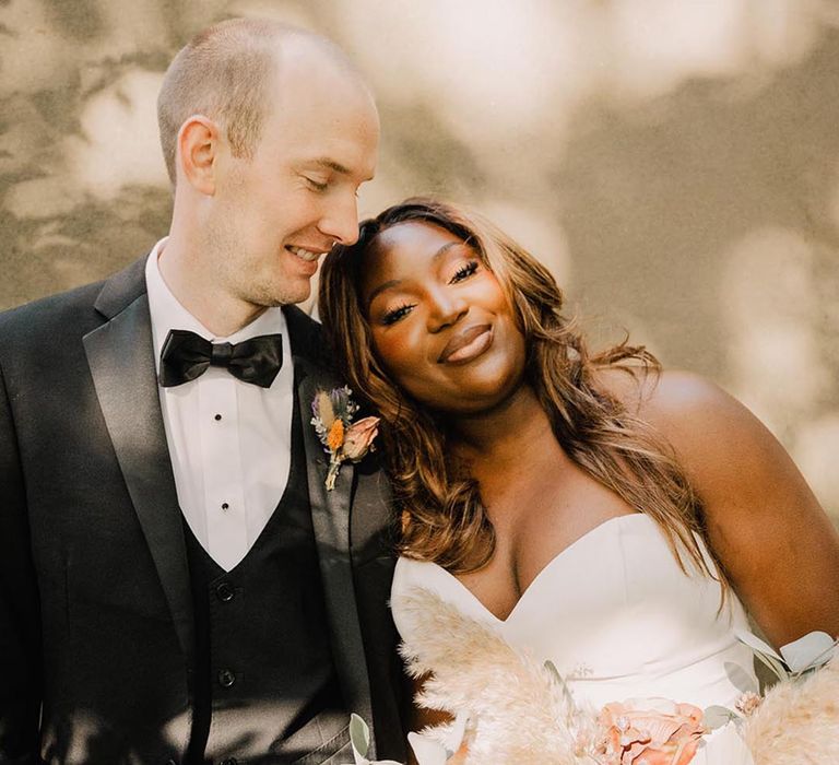 Romantic couple portrait with bride in sweetheart strapless wedding dress with groom in black and white tuxedo 