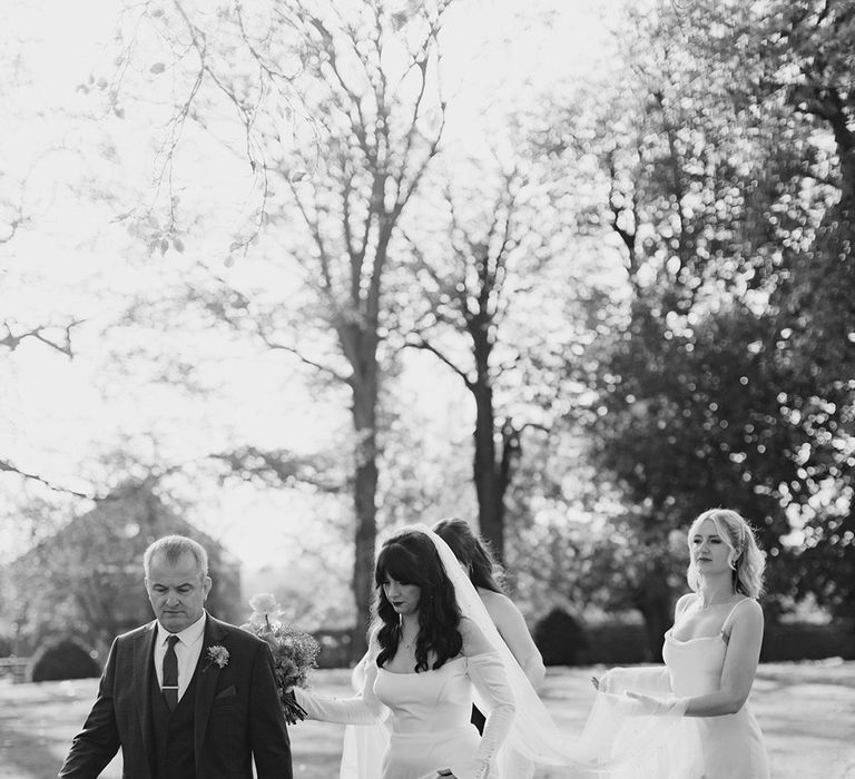 Father of the bride walking to the ceremony with the bride and bridesmaids 