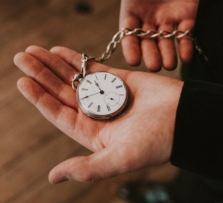 Groom holding silver pocket watch groom accessory for wedding day 