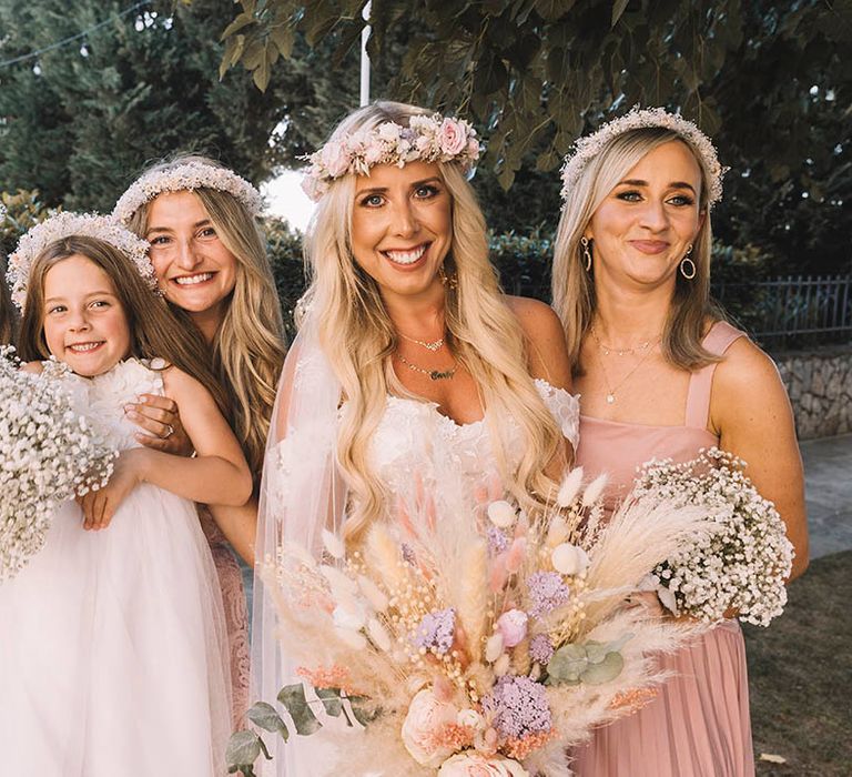 Bride and bridal party wearing pink bridesmaid dresses with flower crowns for pastel boho wedding theme 