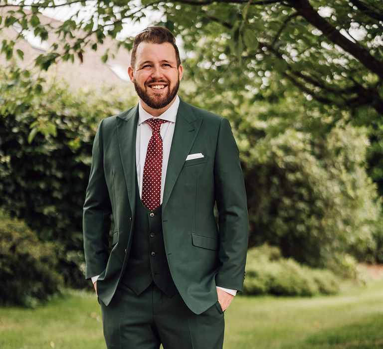 Groom in dark green wedding suit with dark brown polka dot tie 