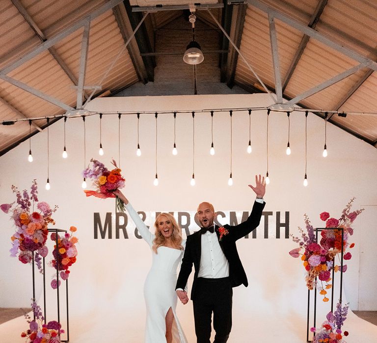 Bride in Suzanne Neville wedding dress with groom in black tuxedo making their wedding breakfast entrance 