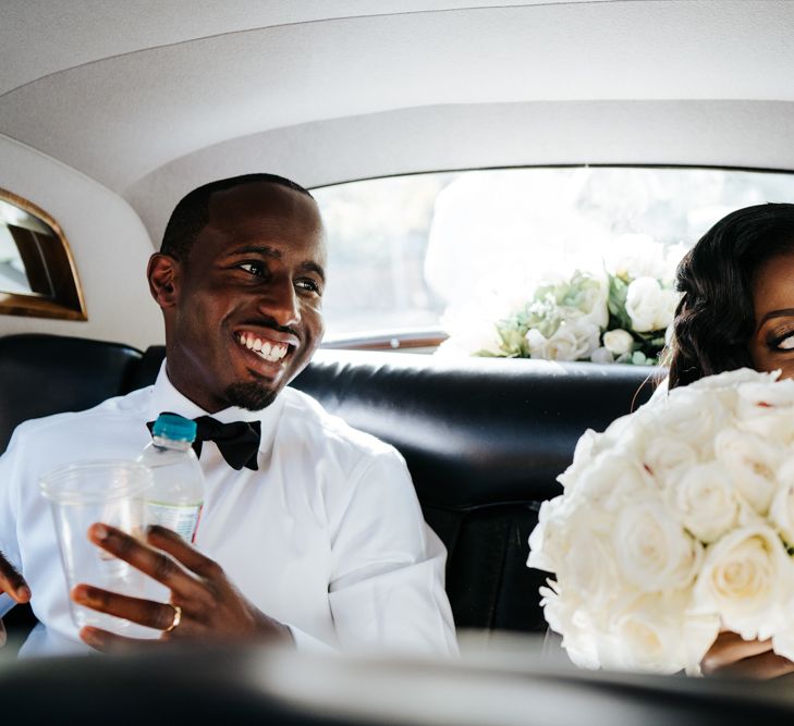 Bride and groom sitting in the back of their vintage wedding car 