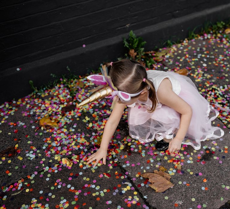 Flower girl with unicorn headband playing with the confetti 