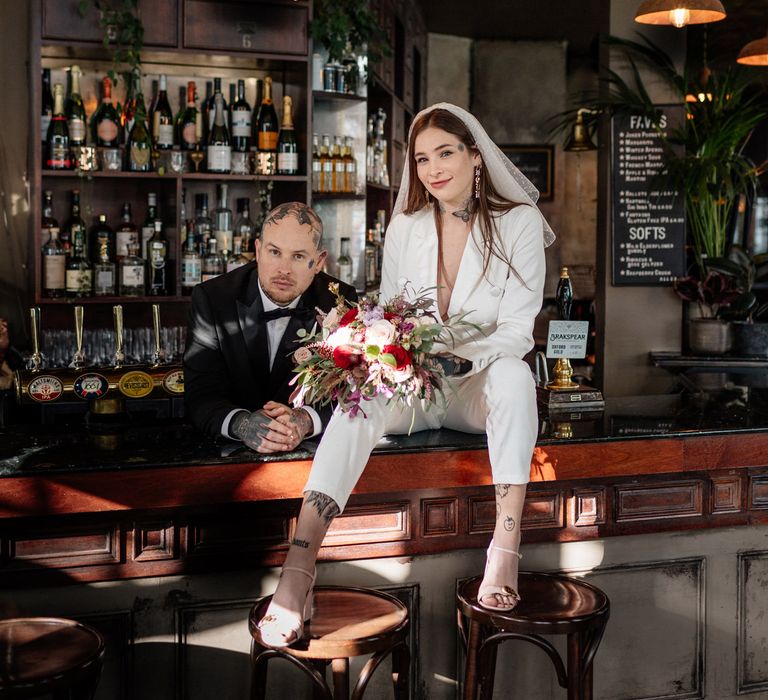 Bride and groom sitting on the bar at Brighton pub reception 