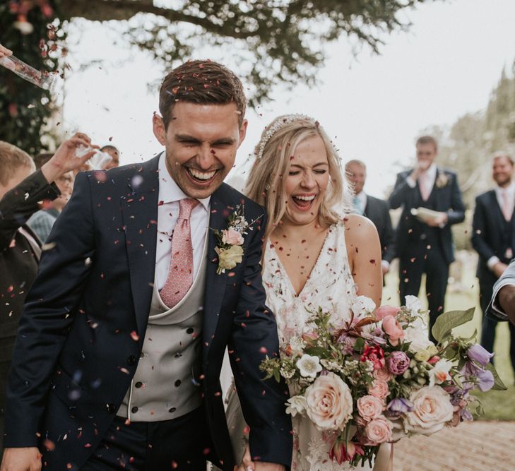 Bride and groom laughing during their confetti exit 