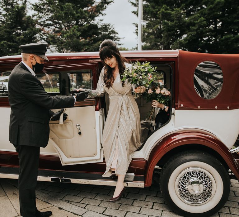 Bridesmaid arrives in vintage car holding floral bouquet 