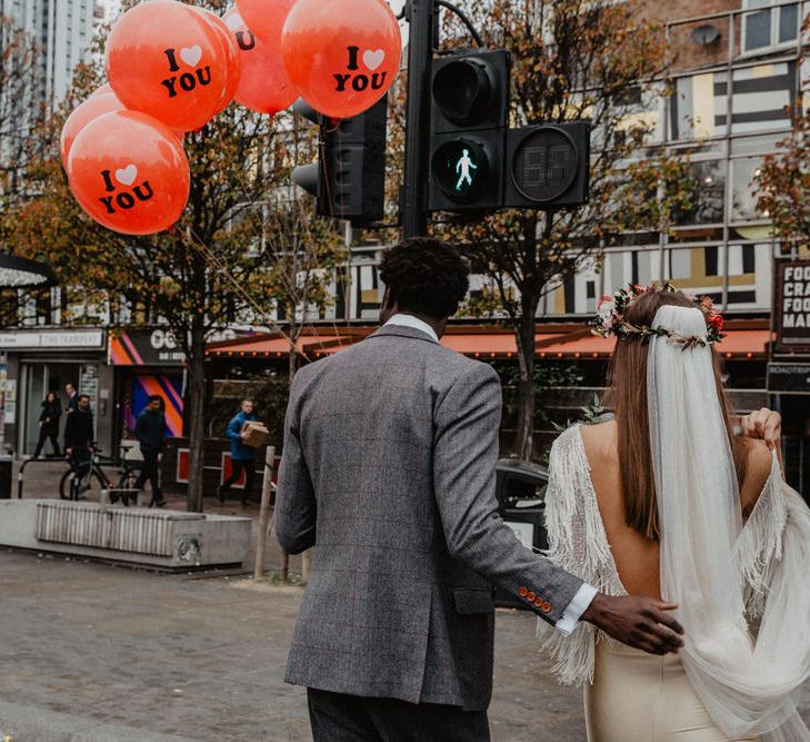 Bride and Groom walk through Shoreditch, Groom holds red I love you balloons