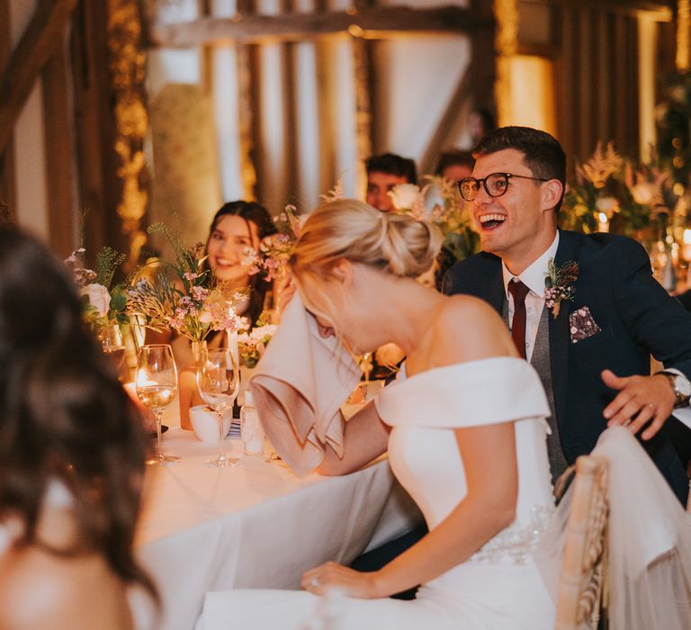 Bride & groom laugh with wedding party during speeches