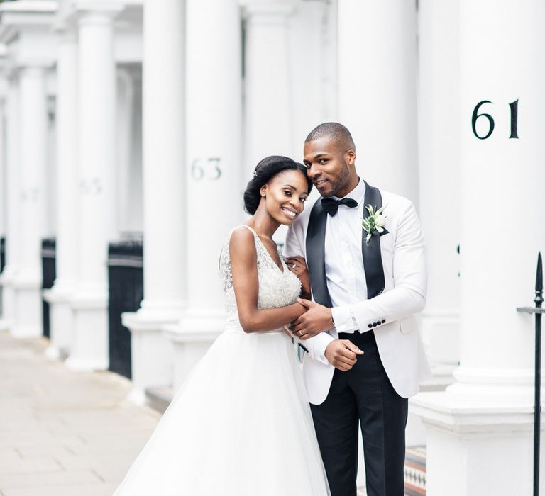 Bride & groom hold hands and lean into one another outside in London